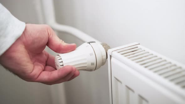 Man Hand Regulates Temperature Knob of Heating Radiator for Heating Room alt