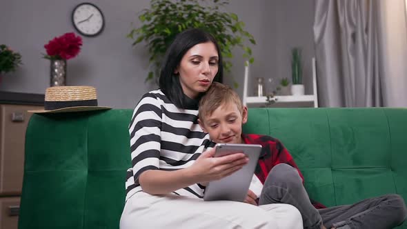 Modern Mother and Son Resting Together on Soft Couch at Home and Watching Intersting Apps alt