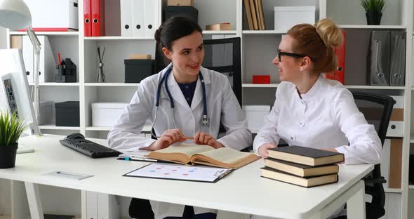 Two Female Doctors Talking in Light Workplace