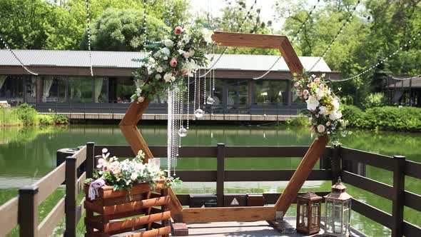 wooden wedding arch for the ceremony in the park near the water alt