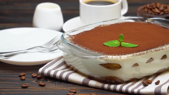 Tiramisu Dessert in Glass Baking Dish and Cup of Fresh Hot Espresso Coffee on Wooden Background alt
