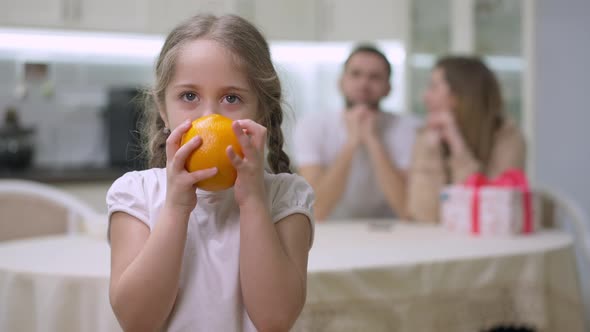 Cheerful Girl Juggling Orange and Smelling Delicious Fruit Looking at Camera Smiling alt