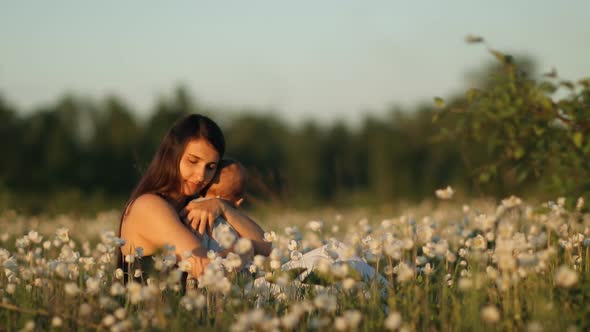 Slow Motion of a Young Happy Mother and Child in a Flower Field at Sunset.