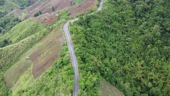 Aerial view of mountain road through tropical forest in countryside by drone