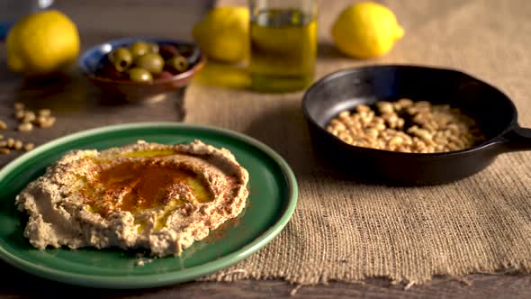 Warm, low angle slide to the left showing middle eastern food spread of olives, pine nuts, hummus, f alt