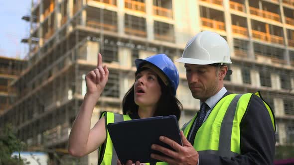 Man and woman discussing with digital tablet at construction site