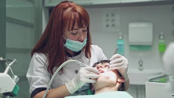 Patient with opened mouth in medical chair treating her teeth with dentist alt