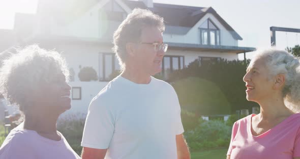 Portrait of happy senior diverse people talking in garden on sunny day at retirement home alt