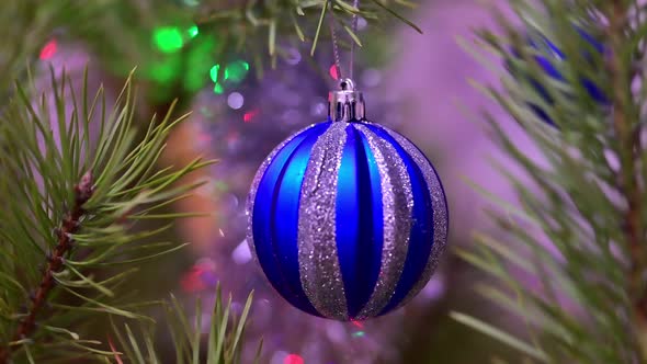 Christmas Tree Decorated with Blue Glass Ball on Christmas Spruce Branch on Background Bokeh of alt
