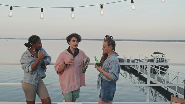 Three Friends Chatting by Lake alt