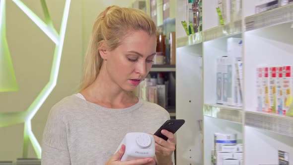 Female Using Smart Phone, Browsing Information Online While Shopping Medication alt