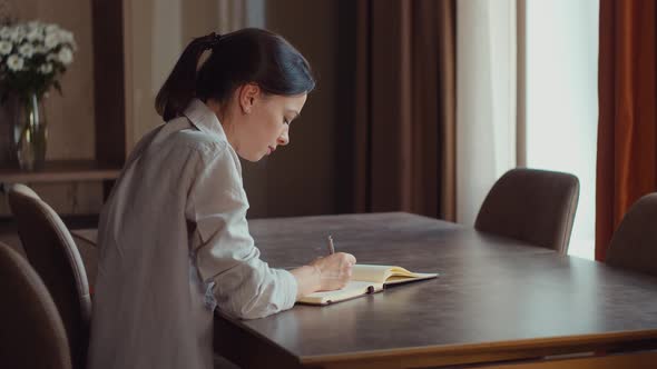 Attractive girl writing to notebook at home alt