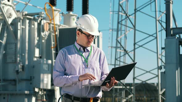 Energetics Specialist with a Laptop Is Checking a Power Station. Energy Efficiency, Energy Saving alt