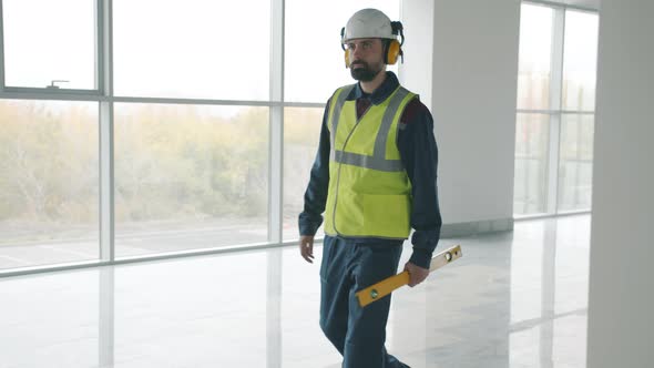 Construction Worker Wearing Uniform Walking Inside Industrial Building Holding Equipment alt