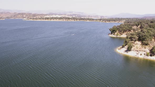 Aerial Drone Tracking Shot of a Boat on a Mountain Lake (Cachuma Lake, California)