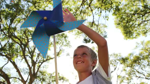 Boy playing with pinwheel in park alt