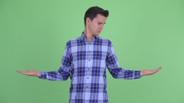 Happy Young Handsome Hipster Man Comparing Something alt