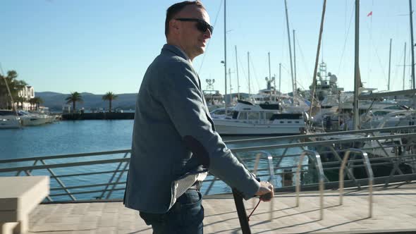 Handsome Business Guy Driving on Scooter Gadget Along the Yacht Mooring