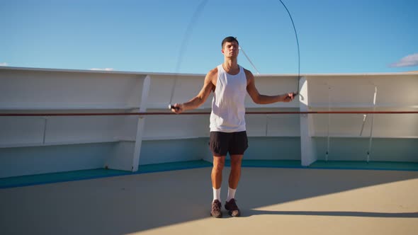 Handsome Athletic Young Man in White Tshirt Jumps on Rope Onboard Cruise Ship