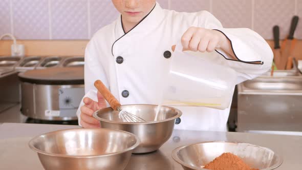 Redhaired Boy in Chef's Costume Cooks Pancakes in Kitchen Kneads Dough Assistant Makes Breakfast