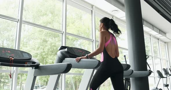 Strong Pretty Woman Training on Running Simulator in Sport Club. Athlete Female Doing Sport-walking alt