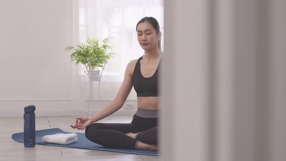 Asian woman does morning yoga, sitting in Easy position, Sukhasana posture, and meditating. alt