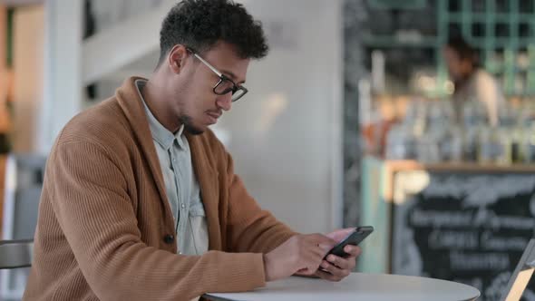 African Man Having Loss While Using Smartphone alt