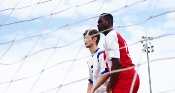 Two football players jumping to strike a ball alt