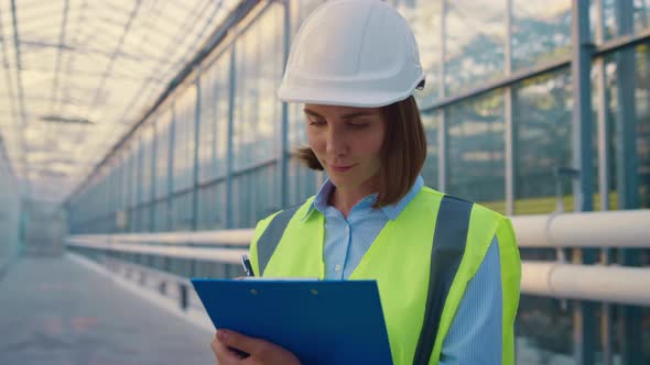 Woman Engineer Making Notes Analysing Production Data in Modern Glasshouse alt