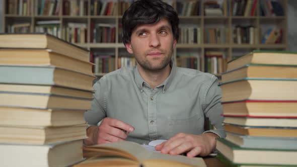 Man Works at a Desk in the Library Having a Great Idea Pointing His Finger Up alt