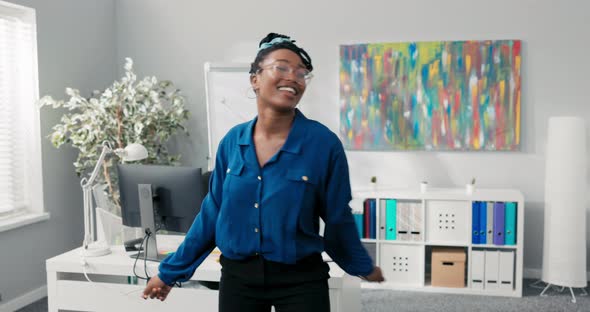 Elegant Feisty Girl Dressed in Blue Shirt and Stylish Glasses Dancing in the Middle of the Office alt