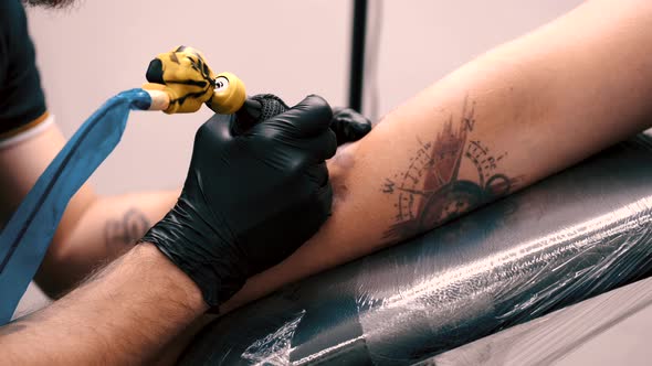 Male Tattoo Artist Tattooing a Client alt