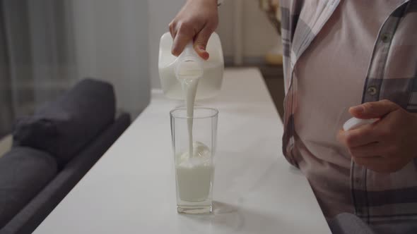Unrecognizable Woman Pouring Glass of Milk From Plastic Bottle Indoors alt