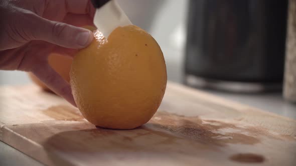 Food Preparation. Man Cutting Orange With Knife Closeup alt