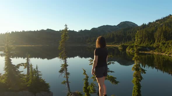 Girl Standing on Tree Stump Looking Out Over Scenic Lake alt