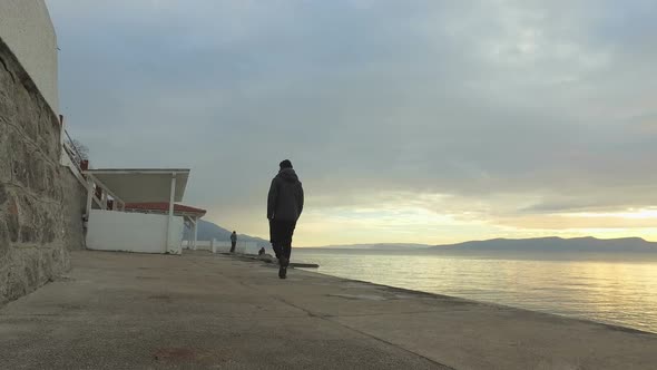 Man walking along seafront walkway alt