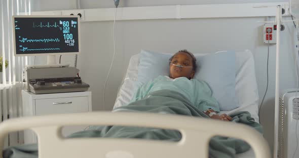 African Kid with Nasal Oxygen Tube Lying in Hospital Bed alt