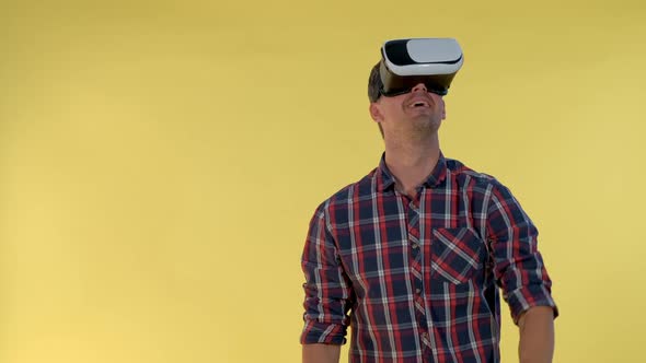 Dark-haired Man Using Virtual Reality Glasses While Standing Against Yellow Background. alt