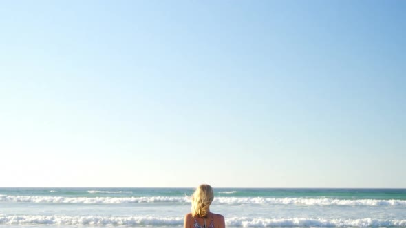 Woman standing on shore at beach on a sunny day alt