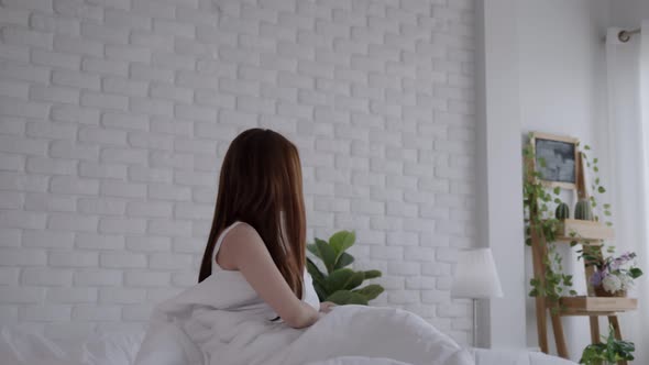 Asian women wake up happy and smile on white bed in bedroom. alt