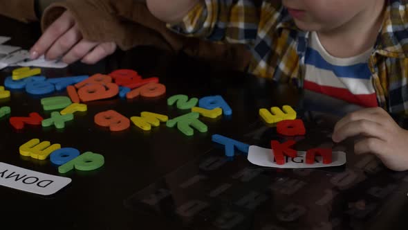 Mom teaches her son how to say the words on the cards and letters at home at the table