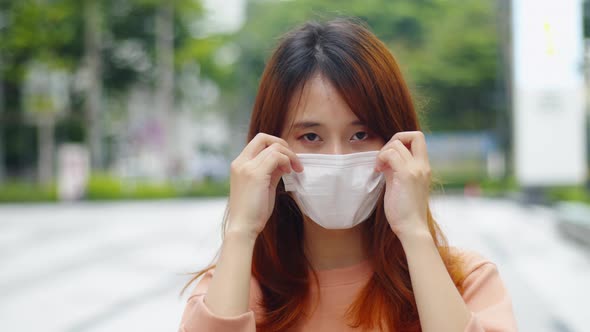 Young asian woman wanting medical face mask standing on the street during virus pandemic