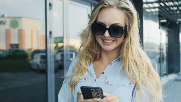 Woman in Sunglasses Standing With Smartphone