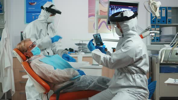 Doctor in Protection Equipment Explaining Dental Problem Using X-ray alt