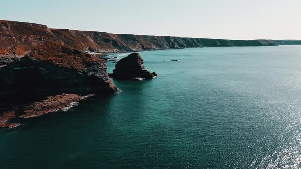 Rocks off the ocean coast line with turquoise water and dramatic cliffs Aerial view.