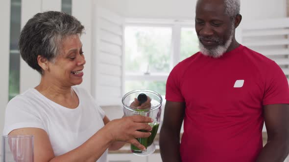 Senior african american man and woman drinking fruit and vegetable health drinks at home alt