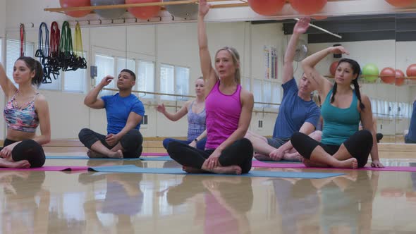 Group of men and women sitting on floor doing yoga at studio