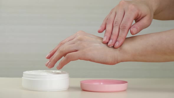 Close-up of a Woman's Hands. The Girl Puts the Cream on Her Hands. The White Texture of the Cream Is alt