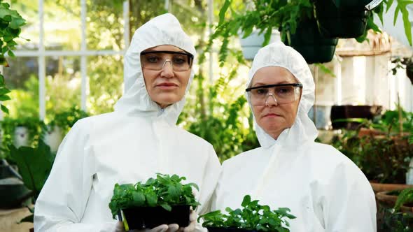 Female scientists holding pot plant alt