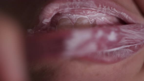 Сlose-up view of person brushing teeth with pink toothbrush and tooth-powder. Morning hygiene. Macro alt